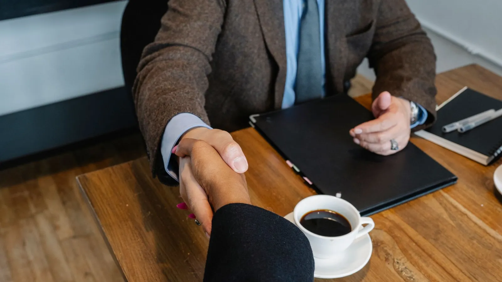Dos personas cerrando un acuerdo comercial en una reunión de trabajo